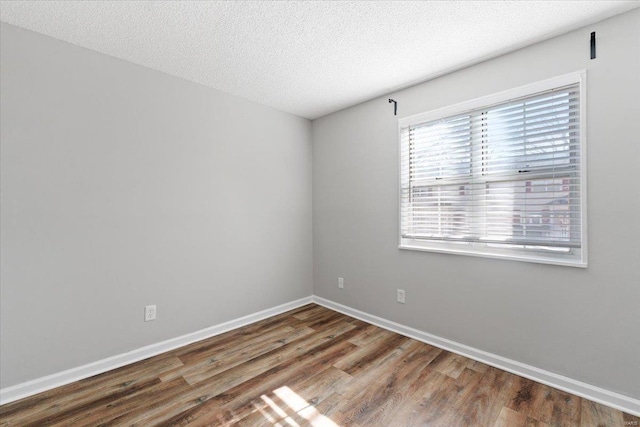 empty room with dark hardwood / wood-style floors and a textured ceiling