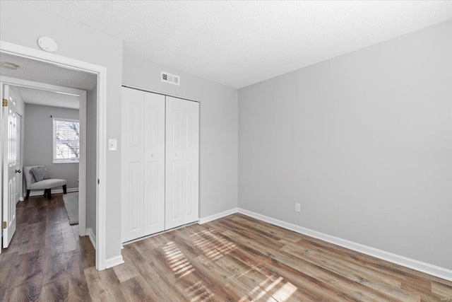 unfurnished bedroom featuring hardwood / wood-style floors, a closet, and a textured ceiling