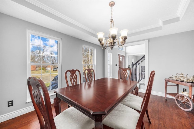 dining room featuring dark wood-type flooring, ornamental molding, a raised ceiling, and a chandelier