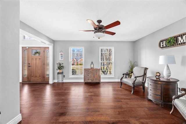 living area featuring dark wood-type flooring, a textured ceiling, and ceiling fan