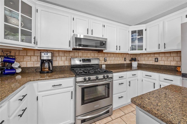 kitchen featuring backsplash, appliances with stainless steel finishes, light tile patterned floors, and white cabinets