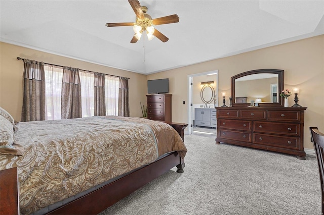 carpeted bedroom with a tray ceiling, ensuite bath, vaulted ceiling, and ceiling fan