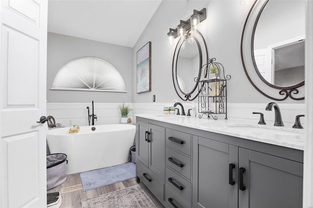 bathroom featuring vanity, hardwood / wood-style floors, a bathtub, and vaulted ceiling