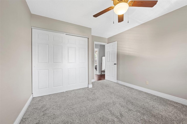 unfurnished bedroom with ceiling fan, a closet, lofted ceiling, and carpet