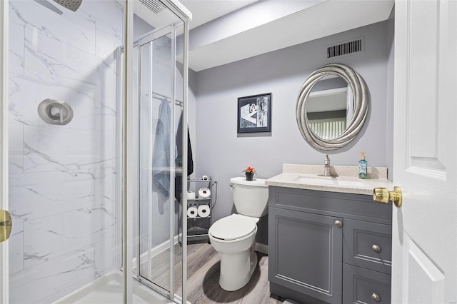 bathroom featuring hardwood / wood-style flooring, vanity, toilet, and a shower with shower door