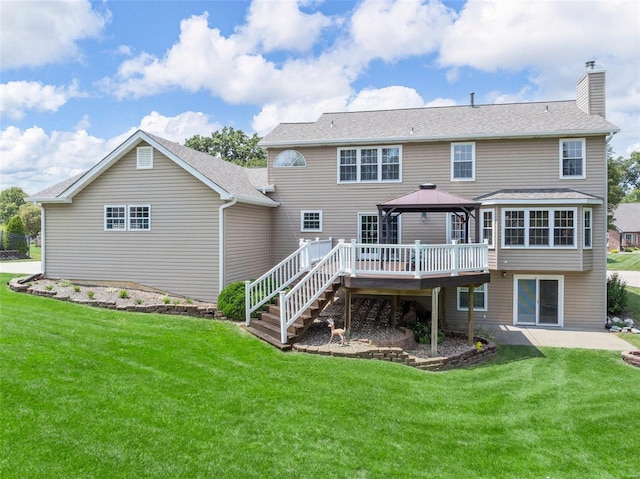 rear view of house with a wooden deck, a gazebo, and a lawn