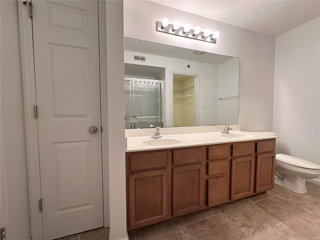 bathroom featuring a shower with door, vanity, and toilet