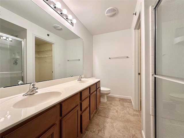 bathroom with vanity, a shower with door, and toilet