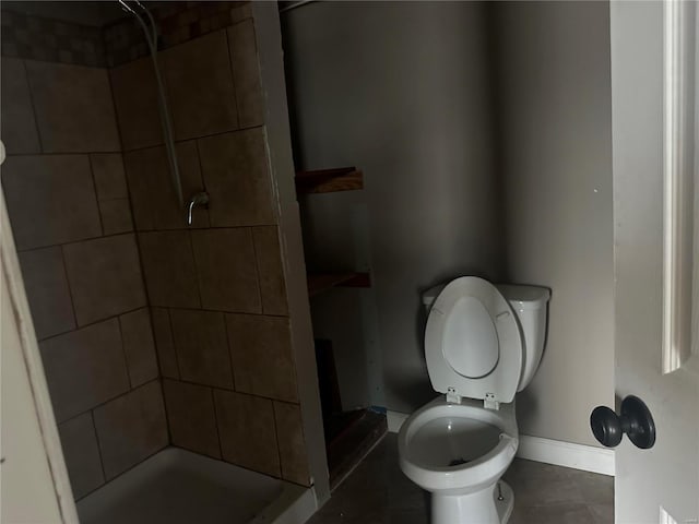 bathroom featuring a tile shower and toilet