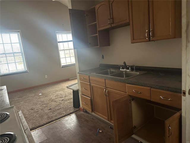 kitchen featuring dark carpet, a healthy amount of sunlight, sink, and dark stone countertops