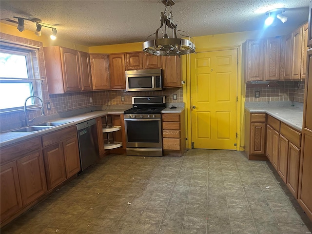 kitchen with pendant lighting, stainless steel appliances, sink, and backsplash