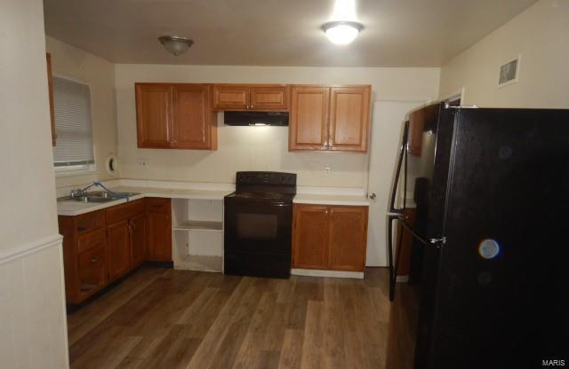 kitchen featuring dark wood-type flooring, sink, and black appliances