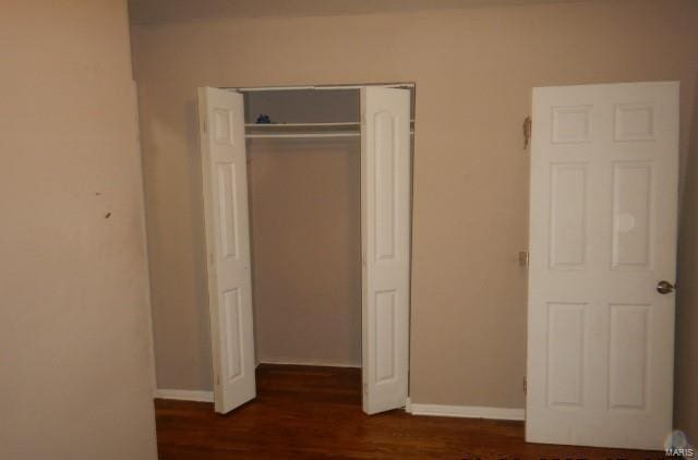 unfurnished bedroom with dark hardwood / wood-style floors and a closet