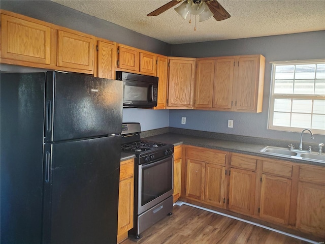 kitchen featuring dark hardwood / wood-style floors, sink, ceiling fan, black appliances, and a textured ceiling