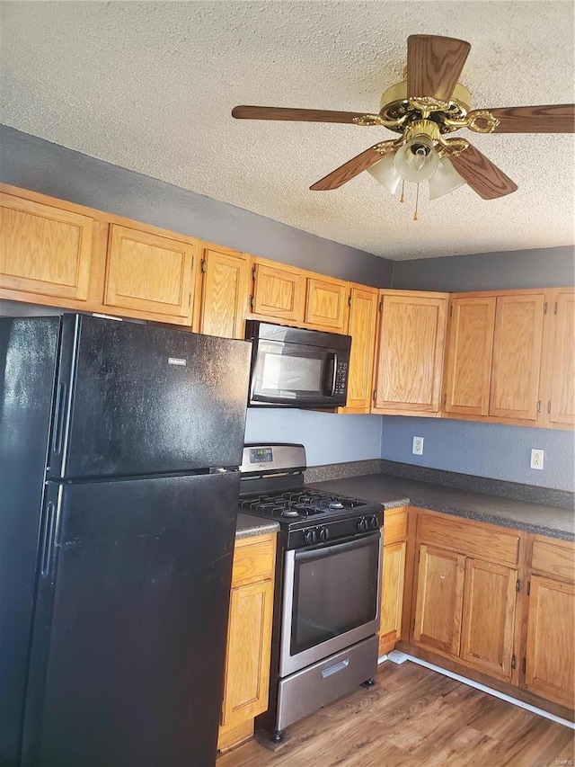 kitchen with ceiling fan, dark hardwood / wood-style floors, a textured ceiling, and black appliances