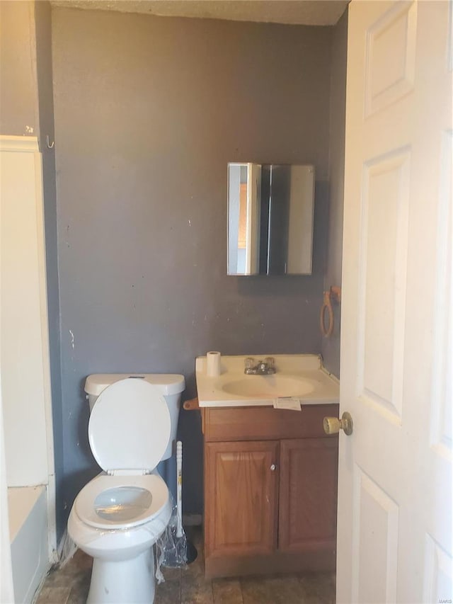 bathroom with vanity, a tub to relax in, and toilet