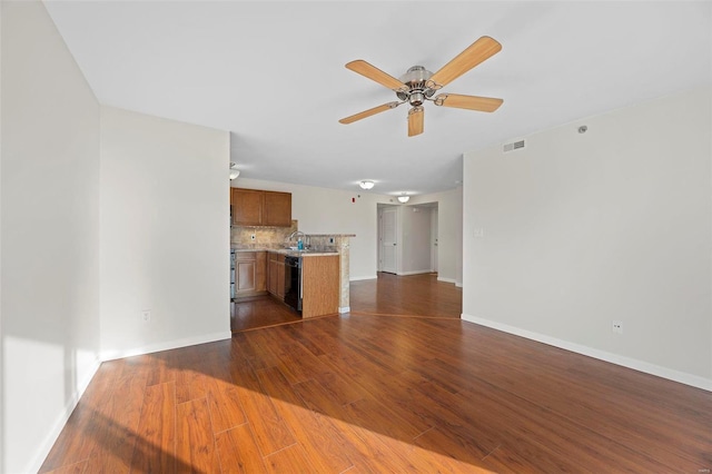 unfurnished living room featuring dark wood-style floors, visible vents, a ceiling fan, a sink, and baseboards