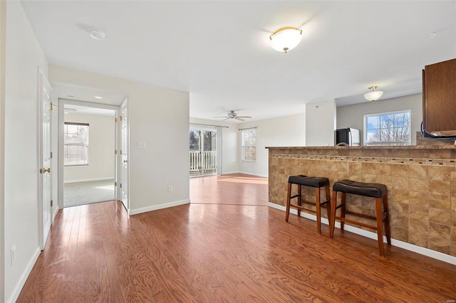 kitchen featuring plenty of natural light, a kitchen breakfast bar, wood finished floors, and freestanding refrigerator