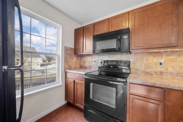 kitchen with baseboards, decorative backsplash, wood finished floors, light countertops, and black appliances