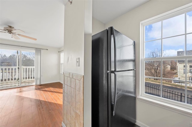 kitchen featuring ceiling fan, baseboards, wood finished floors, and freestanding refrigerator