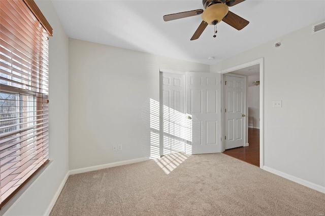 spare room featuring carpet, visible vents, and baseboards