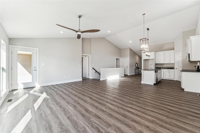 unfurnished living room featuring visible vents, baseboards, dark wood finished floors, and ceiling fan with notable chandelier