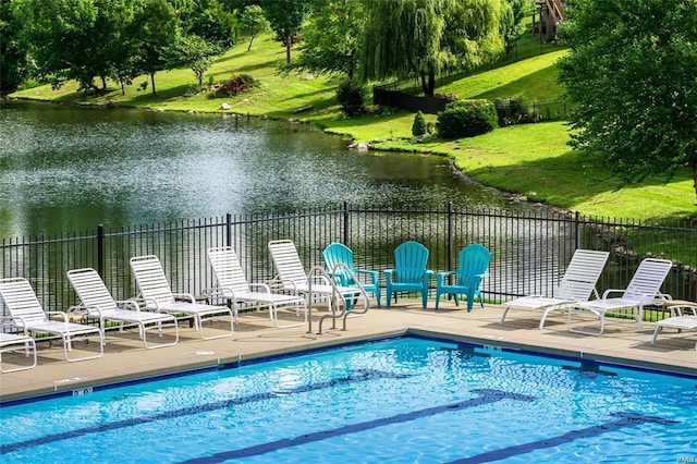 pool featuring a patio area, a water view, and fence