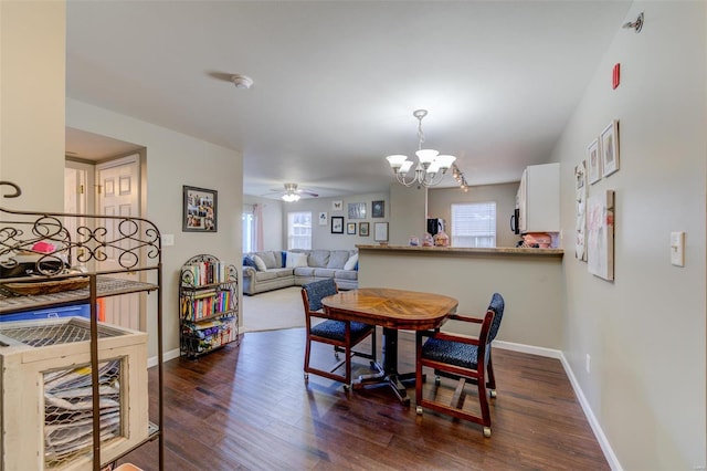 dining area with dark hardwood / wood-style flooring and ceiling fan with notable chandelier