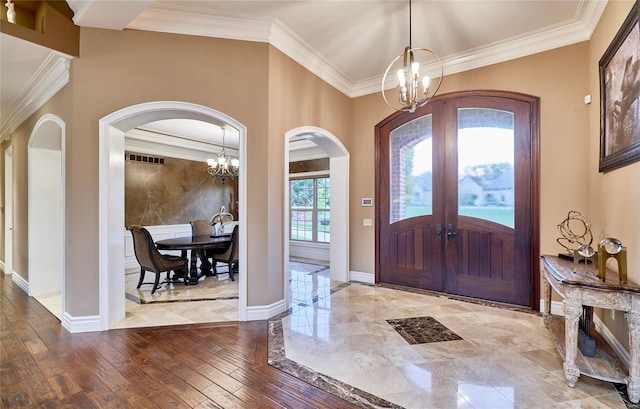 entrance foyer featuring ornamental molding, light hardwood / wood-style flooring, an inviting chandelier, and french doors