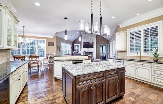 kitchen featuring pendant lighting, sink, dark brown cabinets, a kitchen island, and a chandelier