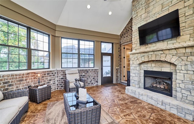 living room featuring a stone fireplace and high vaulted ceiling