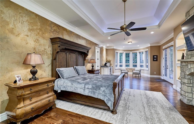 bedroom featuring a fireplace, crown molding, dark hardwood / wood-style floors, and a raised ceiling