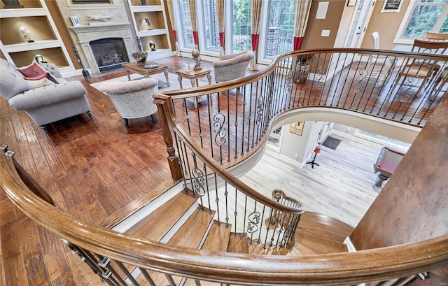 stairs featuring wood-type flooring, built in features, and a wealth of natural light