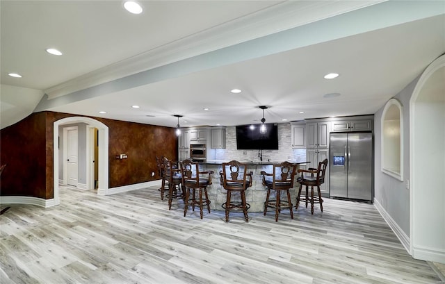 dining area with crown molding, indoor bar, and light hardwood / wood-style floors