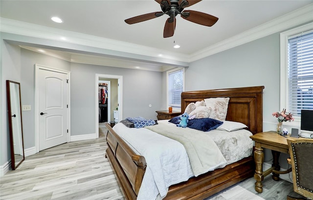 bedroom with crown molding, a walk in closet, ceiling fan, and light hardwood / wood-style flooring