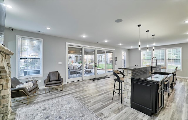 kitchen with pendant lighting, a kitchen island with sink, a breakfast bar area, and plenty of natural light