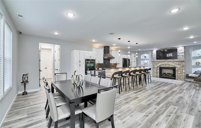 dining space with a stone fireplace and light hardwood / wood-style flooring