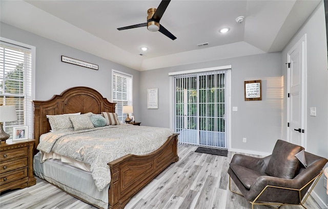 bedroom with light hardwood / wood-style flooring, a raised ceiling, ceiling fan, and access to outside