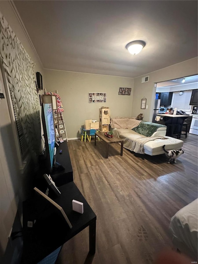 bedroom featuring stainless steel refrigerator, ornamental molding, and wood-type flooring