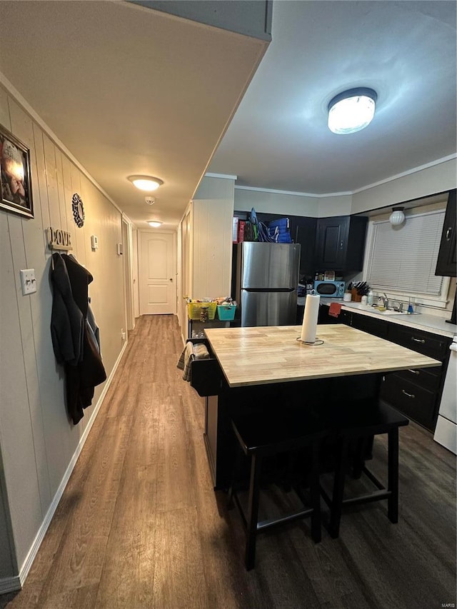 kitchen with hardwood / wood-style flooring, a breakfast bar area, stainless steel refrigerator, wooden counters, and a kitchen island