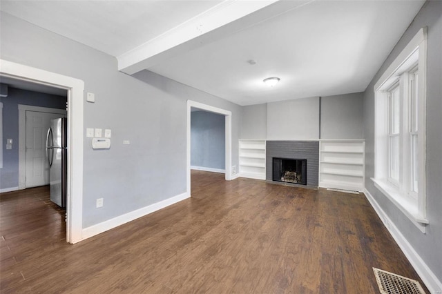 unfurnished living room featuring beam ceiling and dark wood-type flooring