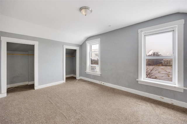 unfurnished bedroom with lofted ceiling, carpet floors, and multiple closets