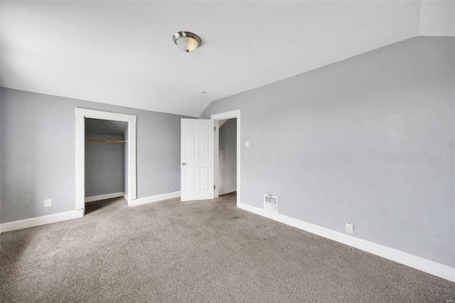 unfurnished bedroom featuring carpet floors, vaulted ceiling, and a closet