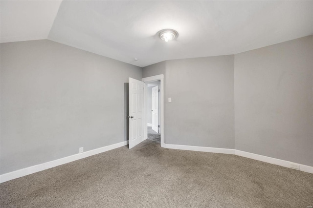 carpeted spare room featuring vaulted ceiling