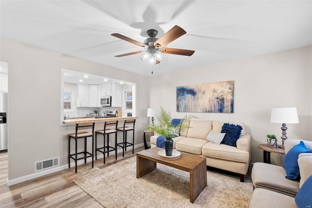 living room featuring ceiling fan and light wood-type flooring