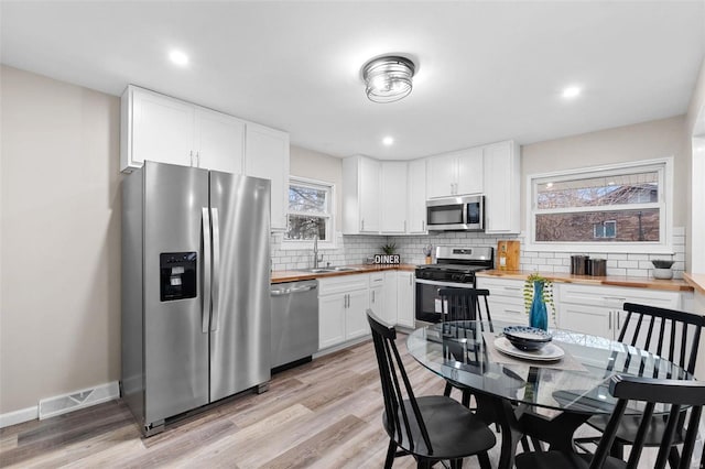 kitchen featuring white cabinetry, sink, stainless steel appliances, and wooden counters