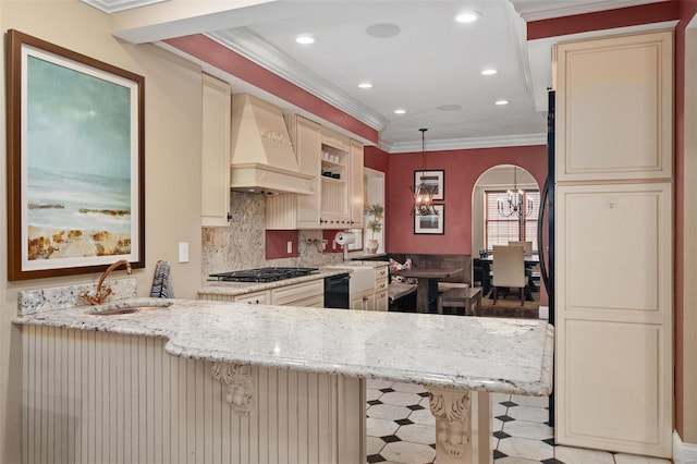 kitchen featuring premium range hood, sink, hanging light fixtures, light stone counters, and kitchen peninsula