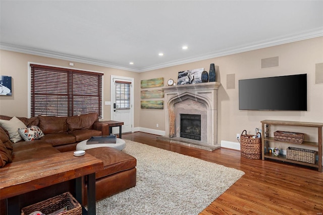 living room featuring hardwood / wood-style flooring, ornamental molding, and a fireplace