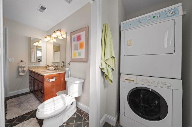 bathroom with stacked washer and dryer, vanity, tile patterned floors, and toilet