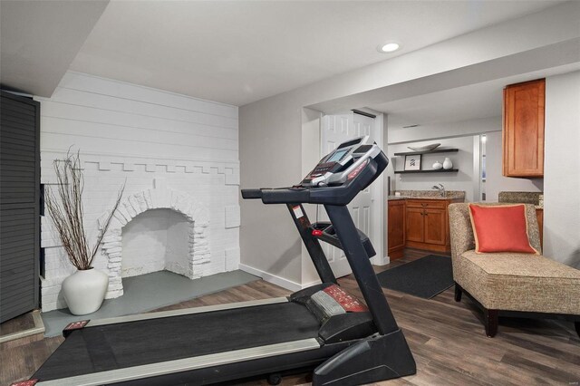 workout area featuring wood-type flooring, a fireplace, and sink